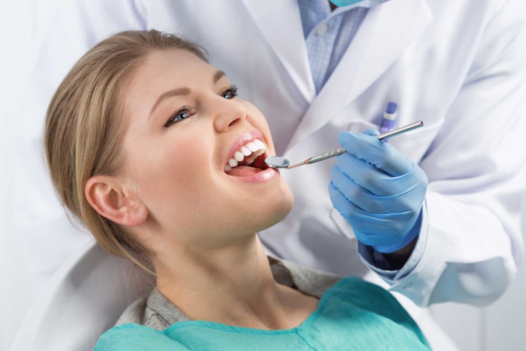 Frau sitzt auf einem Zahnarztstuhl während einer Prophylaxe